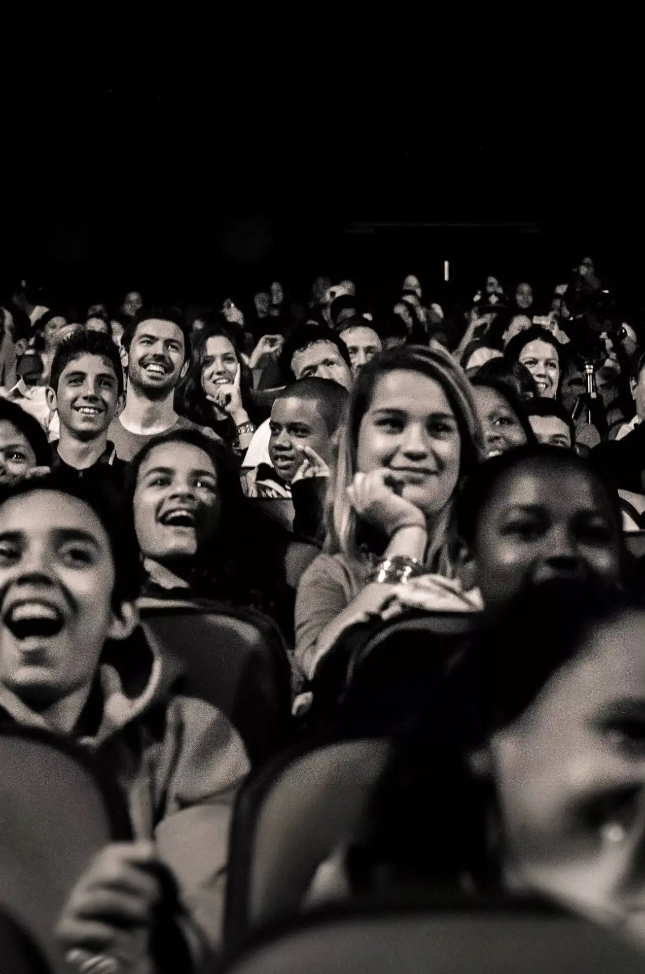 Jovens sentados em um palco de teatro sorrindo